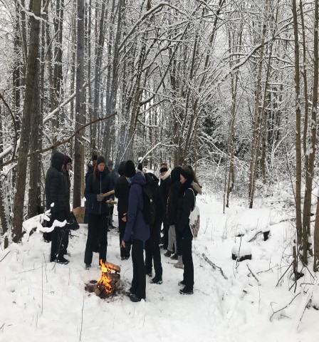 En grupp människor vid en eld i en vintrig skog. Foto.