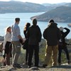 En grupp människor utomhus. I bakgrunden vatten och berg. Foto.