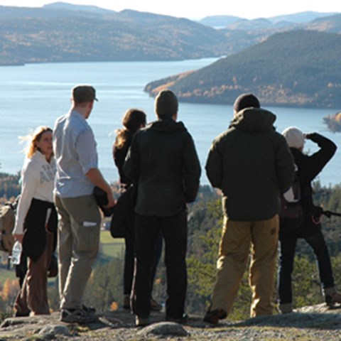 En grupp människor utomhus. I bakgrunden vatten och berg. Foto.
