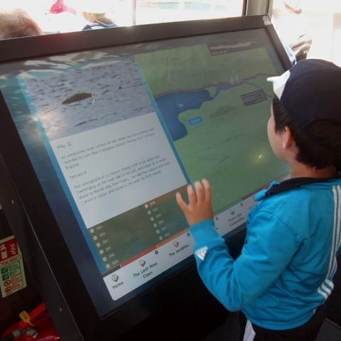 Ung besökare vid interaktiv digital skylt, Loch Ness, Skottland