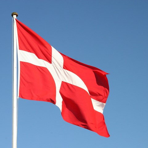 Danska flaggan, röd och vit mot blå himmel.