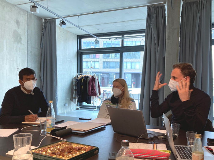 People wearing face masks talking at a table.