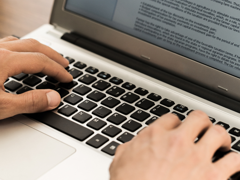 Hands writing on a laptop.