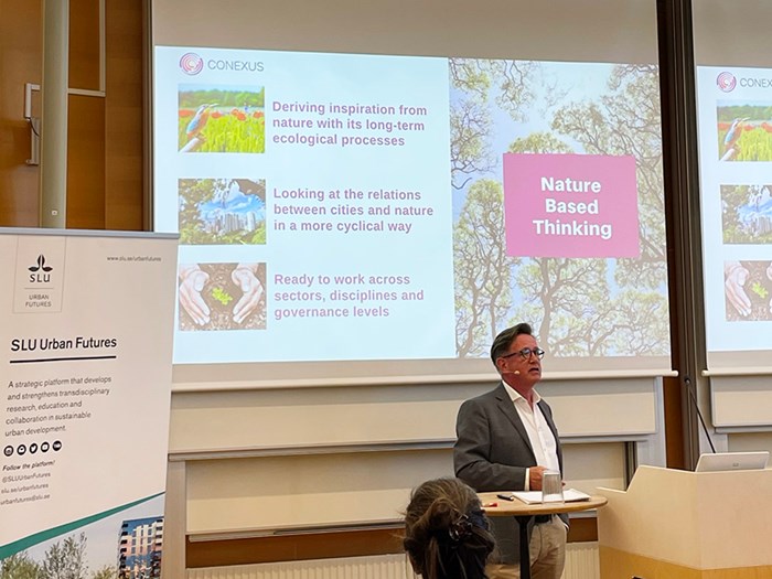 A man in front of a presentation screen.