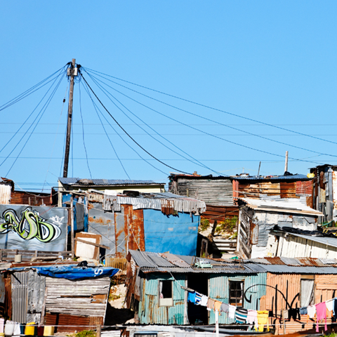 Roofs in an informal settlement under a blue sky.