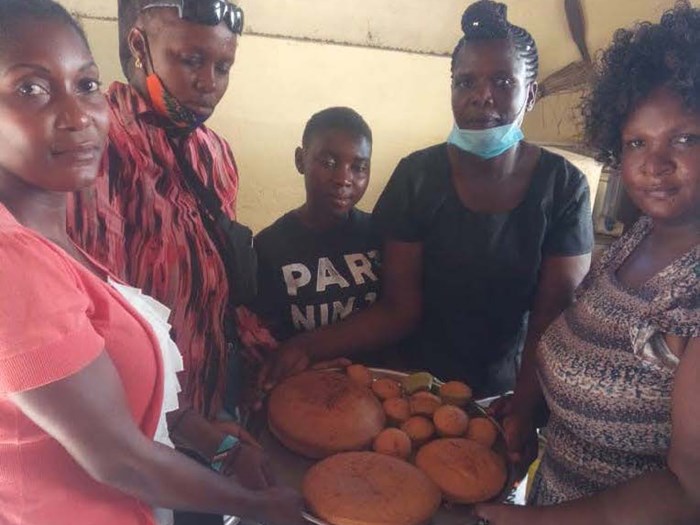 A group of women holding up freshly baked bread.