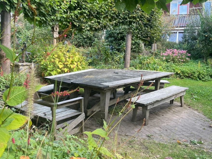 A lush garden with a large wooden table.