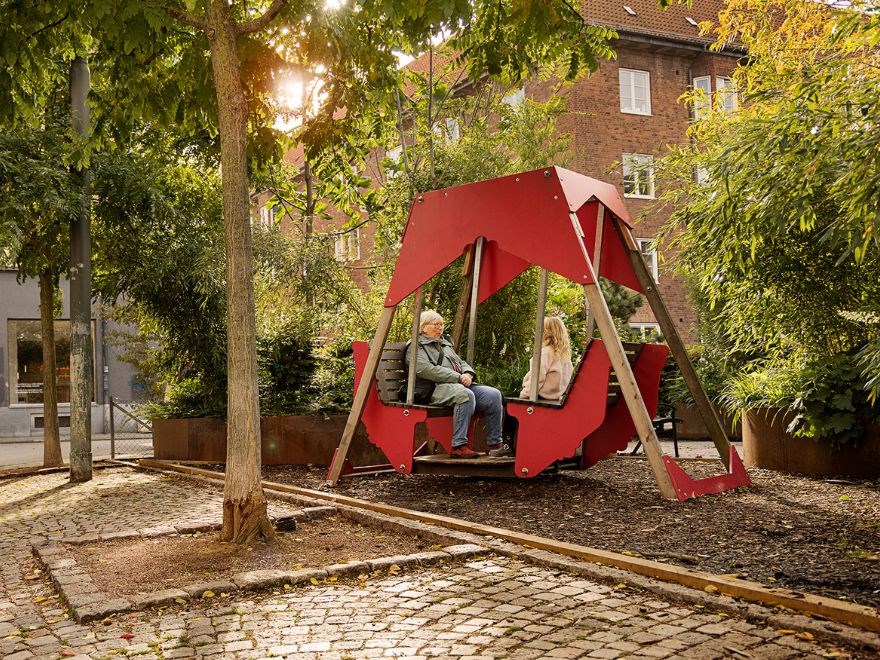 Woman and child sitting in large red swing.
