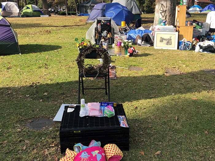 Objects on the ground outside tents in a park.