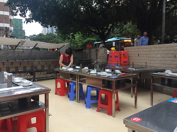 Restaurant in the urban village occupying the transitional zone between street and restaurant, one of dozens that line the street. The urban village housing rises behind the restaurant.