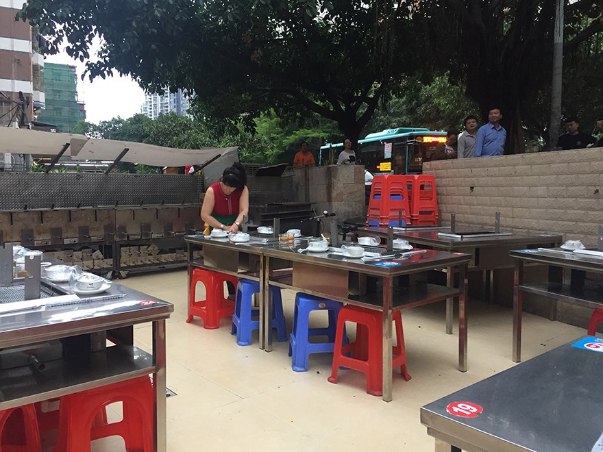 Restaurant in the urban village occupying the transitional zone between street and restaurant, one of dozens that line the street. The urban village housing rises behind the restaurant.