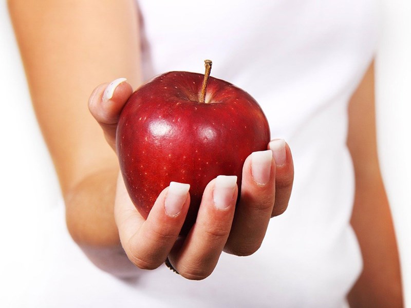Ett rött äpple i en kvinnas hand. Foto.