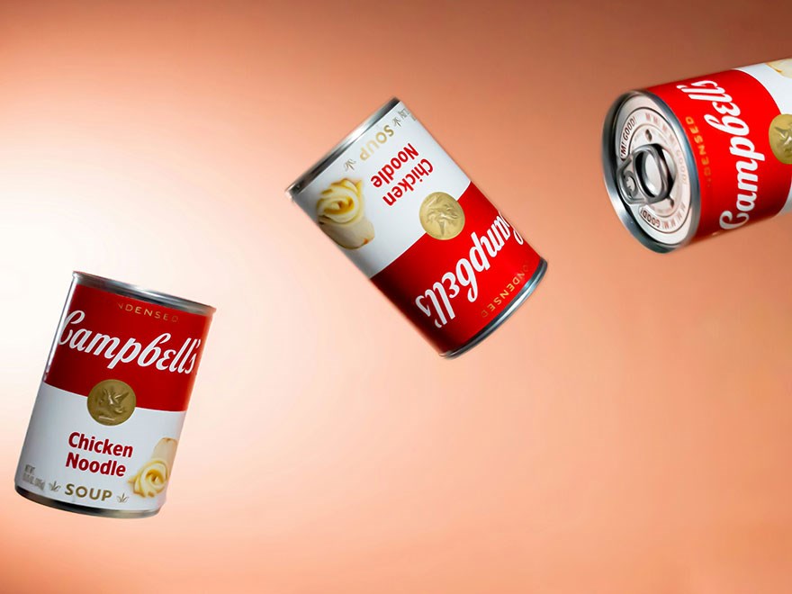 Konservburkar med Campbells soppa flyger genom luften. 