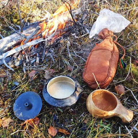 Kåsa och kokkärl vid en eld. Foto.