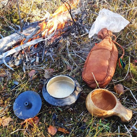Sami cooking utensils by an open fire in the wild. Photo.