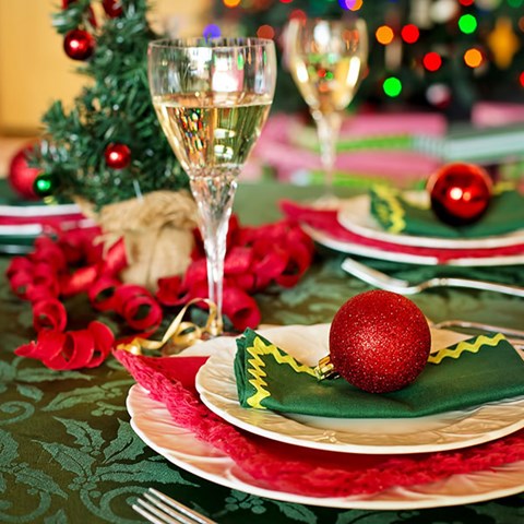 Röda kulor, dekorationer och festliga glas på ett bord. Foto.