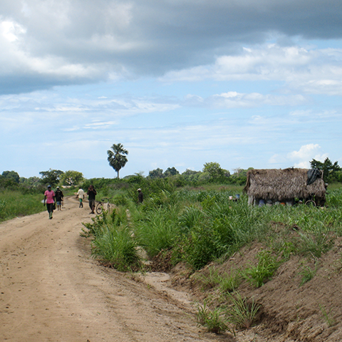 Ett litet hus och några människor på en väg på landsbygden i Tanzania
