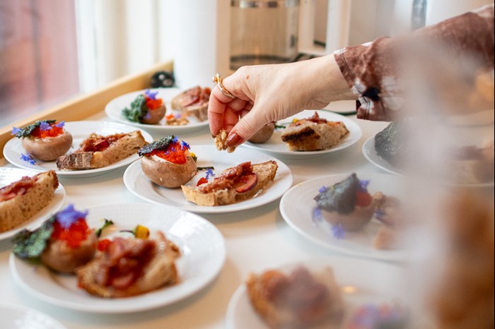 A hand sprinkles spices over plates by a window. Photo.