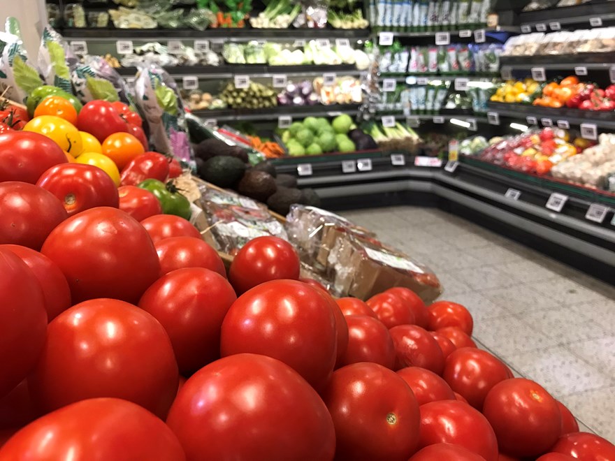 Grönsaksdisk i matvaruaffär, i förgrunden röda tomater. Foto.