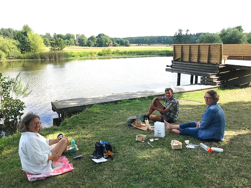 Tre personer har picknick på en grässlänt vid Fyrisån. Foto.