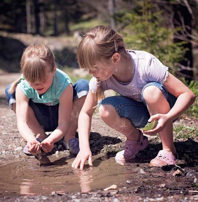 Två barn leker vid en vattenpöl. Foto.