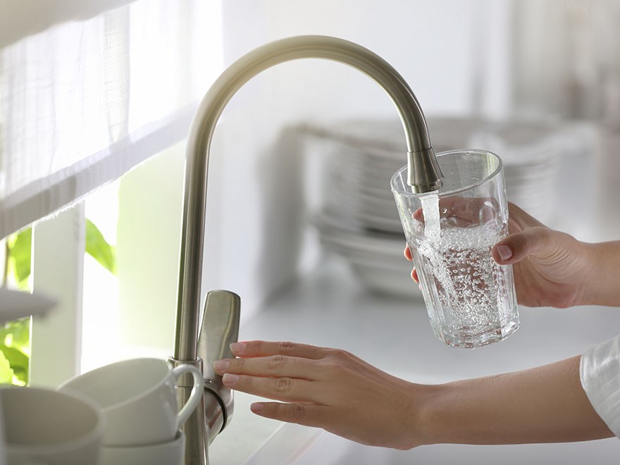 Pouring water in a glass in the kitchen, photo.