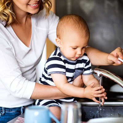 Mother and baby taking water from a tap, photo.