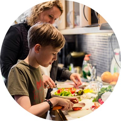 En pojke och hans mamma lagar mat i ett kök. Foto.
