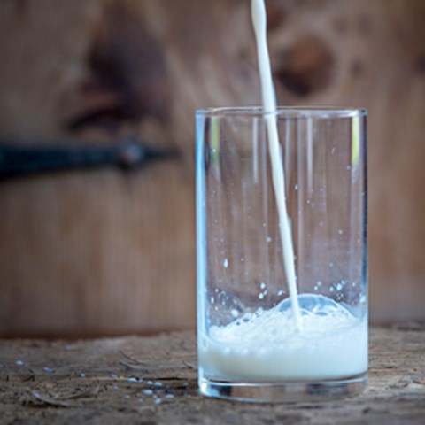 Mjölk hälls ner i ett glas. Foto.