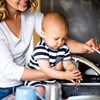 Foto av en mamma med bebis som tar vatten ur kranen. 