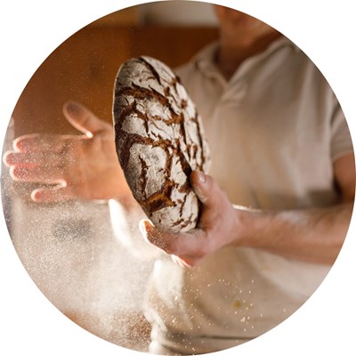 A baker holds a piece of bread. Photo. 