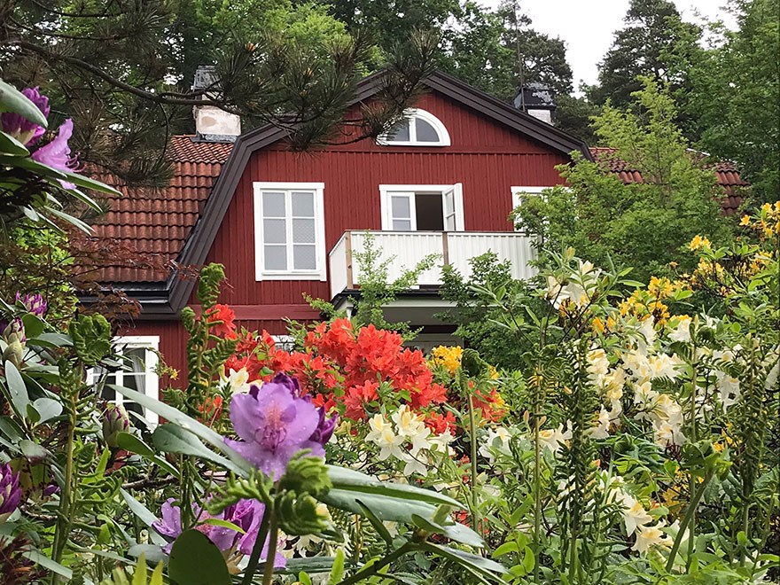 Ett rött trähus inbäddad i grönska, foto.
