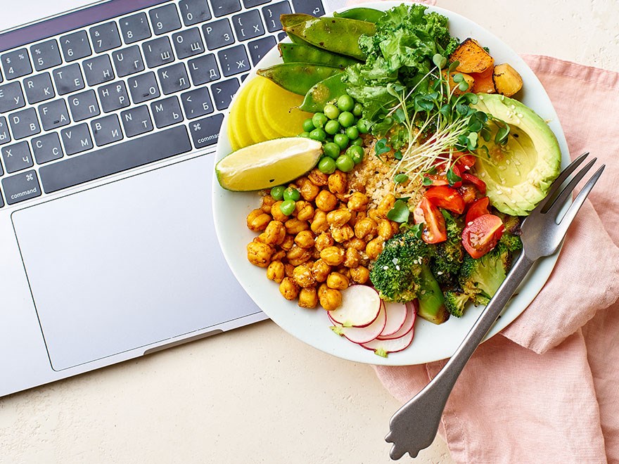 Lunchtallrik bredvid en laptop. Foto.