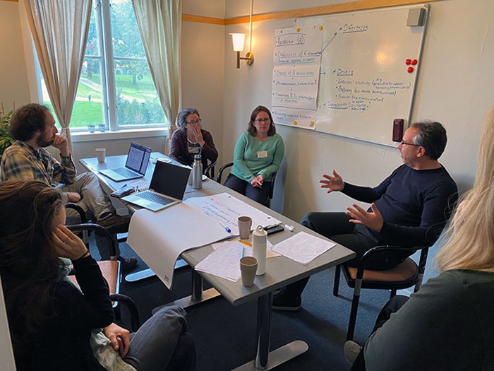 A small group of course participants sit in a small room and discuss.