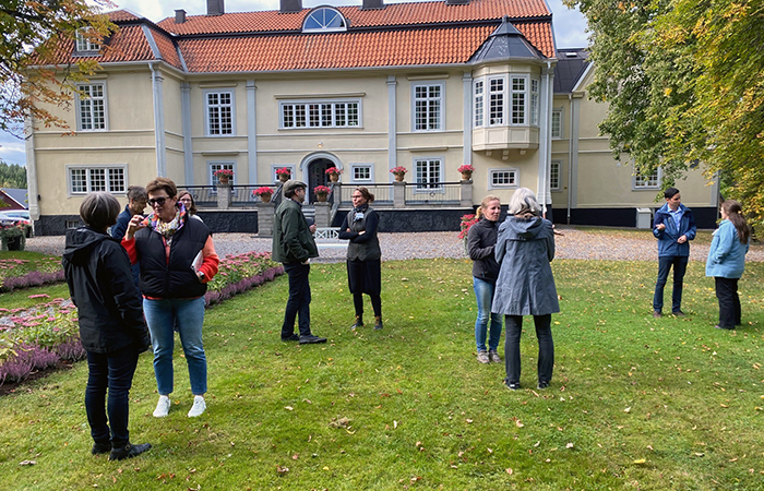A group of people on a lawn in front of Ekenäs mansion. Photo.