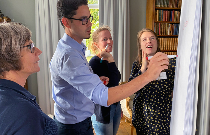 Three women and a man carrying out a group exercise at a whiteboard. Photo.