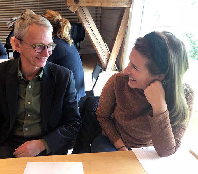 En man och en kvinna ler mot varandra inomhus, foto.