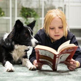 Ett barn och en hund läser tillsammans, foto.