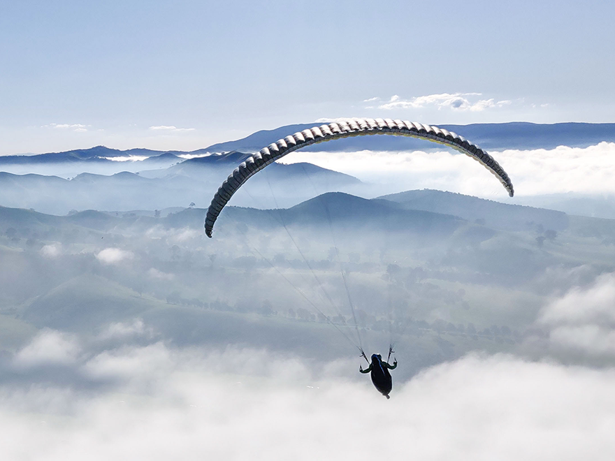 A person paragliding among white clouds. Photo.