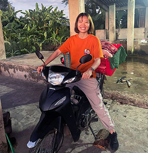 A young Vietnamese woman sitting on a moped. Photo. 