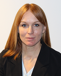 Portrait of Elisabeth Rajala, woman with long red-blonde hair wearing a black blazer. Photo.