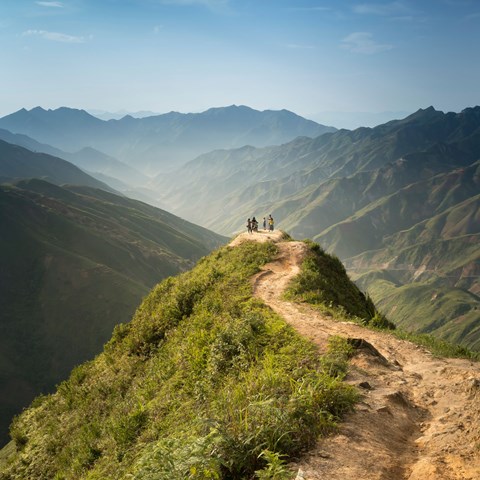 En grupp med människor i ett bergigt och storslaget landskap. Foto.