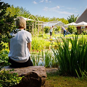 En kvinna sitter i en trädgård, foto.