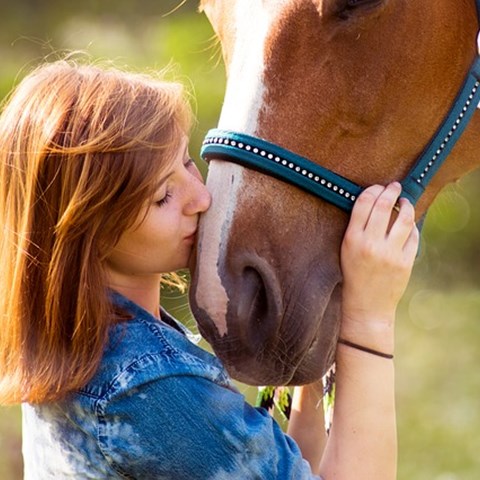 En kvinna och en häst interagerar, foto.