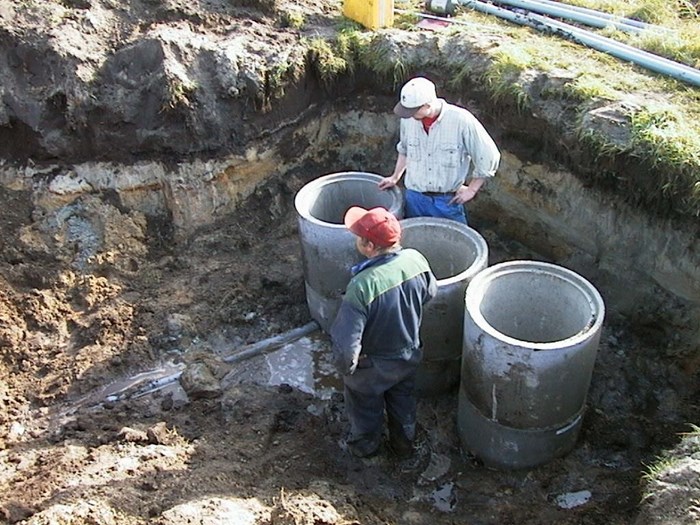 Två personer installerar dämningsbrunnar.