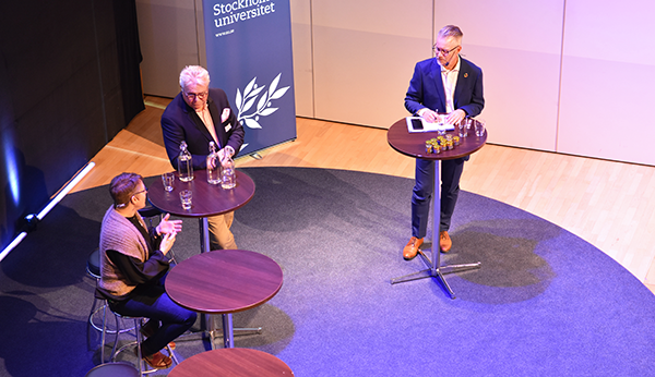 Fågelperspektiv ,tre personer diskuterar vid höga bord
