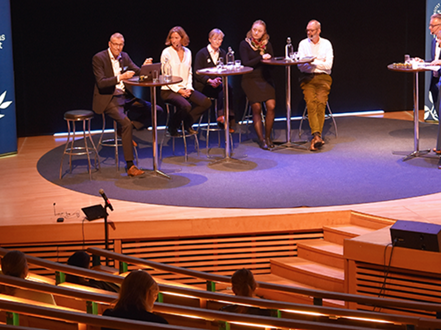 Five persons in conversation on stage