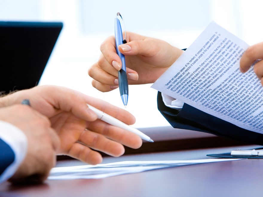 hands holding pens over a desk