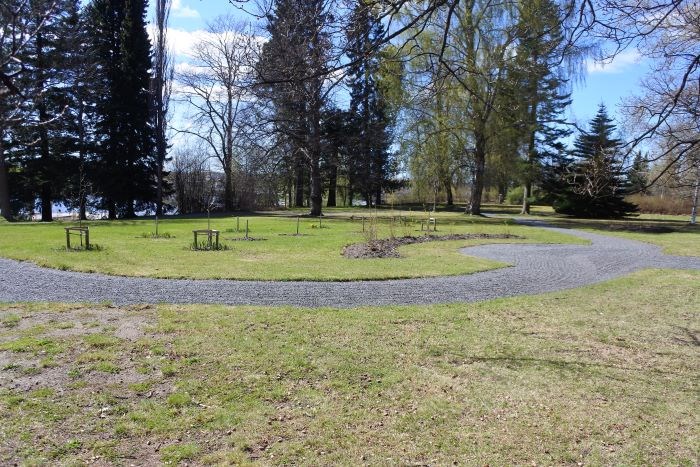 Parken vid länsresidenset, sedd från residensbyggnaden. I förgrunden ses flera nyplanterade träd och buskar. 