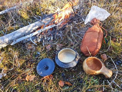 Samiska föremål i gräset bredvid en öppen eld. Foto.